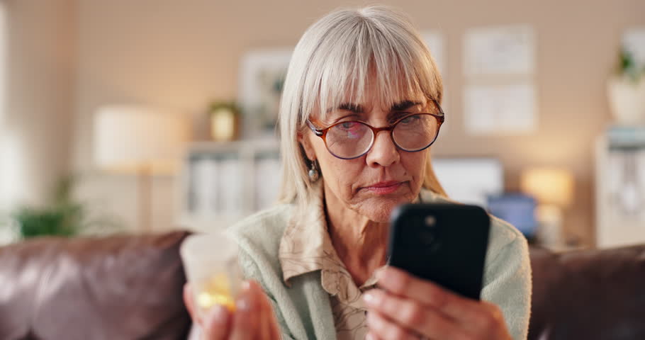 Old woman, phone and pill label in home, search side effects and online for drug information. Elderly person, tablet container and pharmacy website for dosage instructions, bottle check and advice