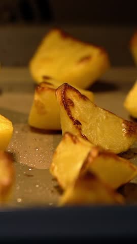 Close up of potato slices are baked in hot oven on baking sheet. Food background. Vertical shot