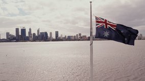 Australian flag waves in the breeze against the Perth skyline and river under gray skies. - Powered by Shutterstock - Get 15% off with code: PIKWIZARD15