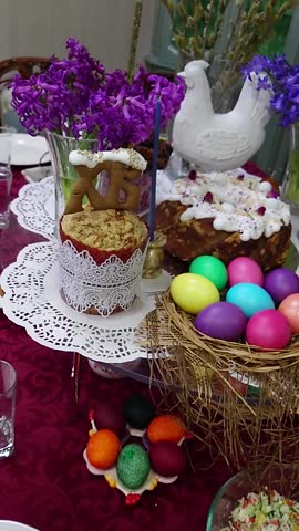 Easter Celebration Table with Decorated Cakes, Colorful Painted Eggs in a Nest, Fresh Flowers, and Festive Symbols of Spring Renewal and Joyful Traditions.