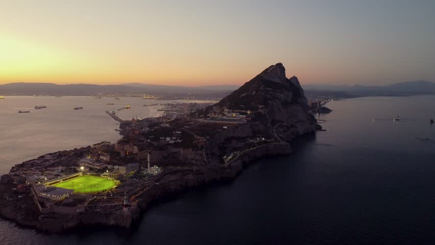 Spectacula aerial view of Gibraltar at sunset. Street lights on. Europa Sports Complex Stadium with night light on. Travel destination. Bay of Gibraltar. City of Gibraltar and La Linea, in background.