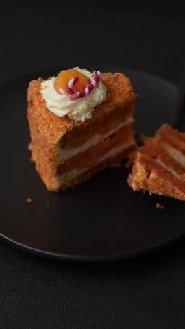 Piece of sweet layer cake with pumpkin or citrus flavor with cream on a dark textured background