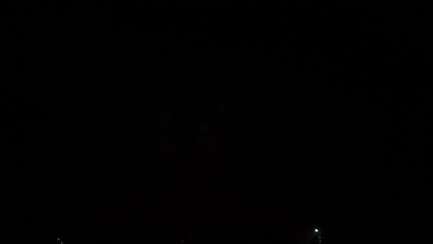 gold red blue sparks scattering fireworks on the black night sky over the city. General plan