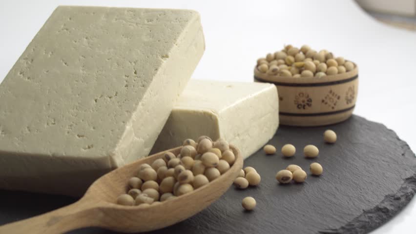 Pieces of raw tofu on a wooden board with soy beans. food concept.