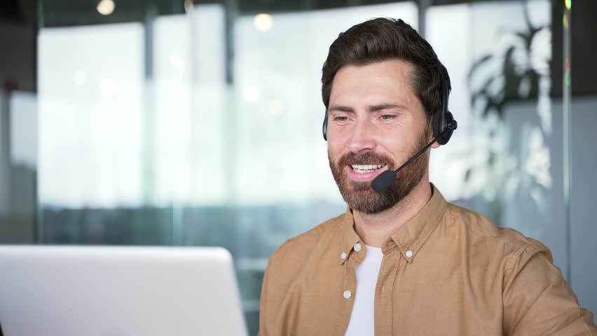 Corporate operator who works in customer support speaks on a video call using a laptop. Call center agent in wireless headset helping customer with complaints in office. Online consultation. Close up - Powered by Shutterstock - Get 15% off with code: PIKWIZARD15