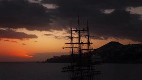 Silhouette drone shot of sailors high up in the mast on a historic Tall ship in the bay during sunset with dramatic clouds in the sky - Powered by Shutterstock - Get 15% off with code: PIKWIZARD15