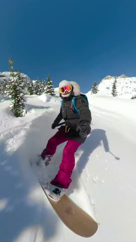 SELFIE: Sporty female tourist snowboards off-trail in the scenic backcountry of British Columbia. Cool selfie shot of an active woman ski touring high in the picturesque Canadian Rocky Mountains.
