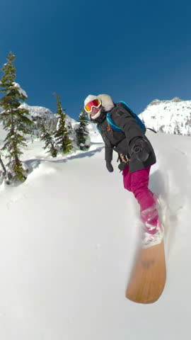 SELFIE: Sporty female tourist snowboards off-trail in the scenic backcountry of British Columbia. Cool selfie shot of an active woman ski touring high in the picturesque Canadian Rocky Mountains.