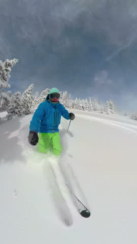 SELFIE: Young man learning to ski rides off piste in the fresh powder snow. Inexperienced skier goes tree skiing in beautiful Park City, Utah. Active male tourist shreds powder in the US mountains.