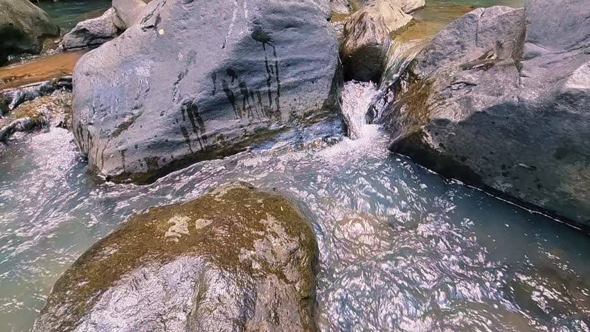 Mountain water flows rapidly amidst very large rocks