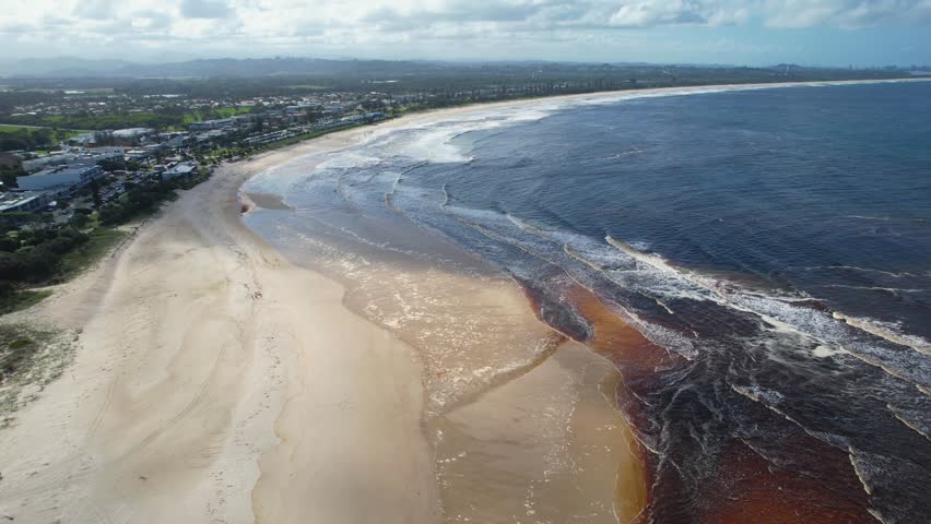 Aerial views of muddy waters from Cudgen Creek flowing in to the sea at Kingscliff headland seawall along the east coast of New South Wales, Australia