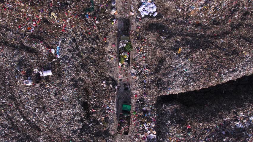 Trucks full of trash moving along big landfill. Garbage dump with non-recyclable waste, unsorted plastic. Human impact to the nature, environmental pollution