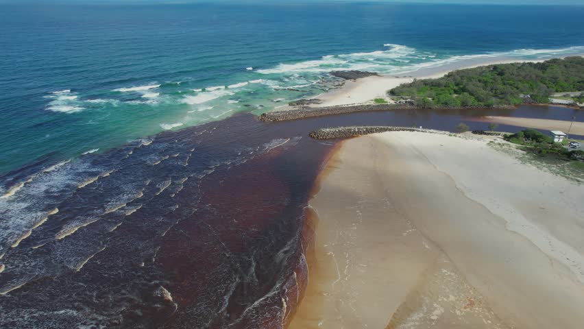 Aerial views of muddy waters from Cudgen Creek flowing in to the sea at Kingscliff headland seawall along the east coast of New South Wales, Australia