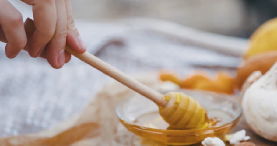 A close-up of a person gracefully using a honey dipper to collect and pour fresh honey into a jar