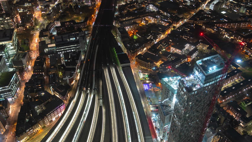 Aerial timelapse view of trains arriving and departing from London Bridge Station at night in London, England.