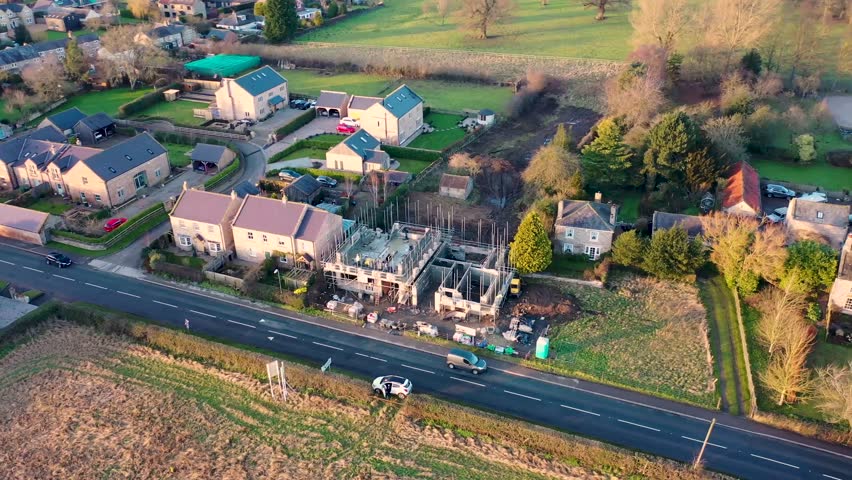 Aerial footage across the beautiful small town of Little Ribston in the Harrogate district of North Yorkshire, England showing a building site with two new houses being built in the early morning