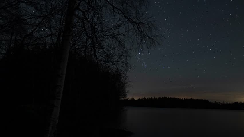 A star tracking time lapse of the Orion constellation in the sky on the wooded shore of a lake in Pirkanmaa, Finland