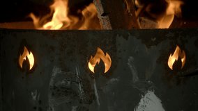 A bonfire is burning in an old, rusty metal brazier, with holes shaped like a flame. Close up. - Powered by Shutterstock - Get 15% off with code: PIKWIZARD15