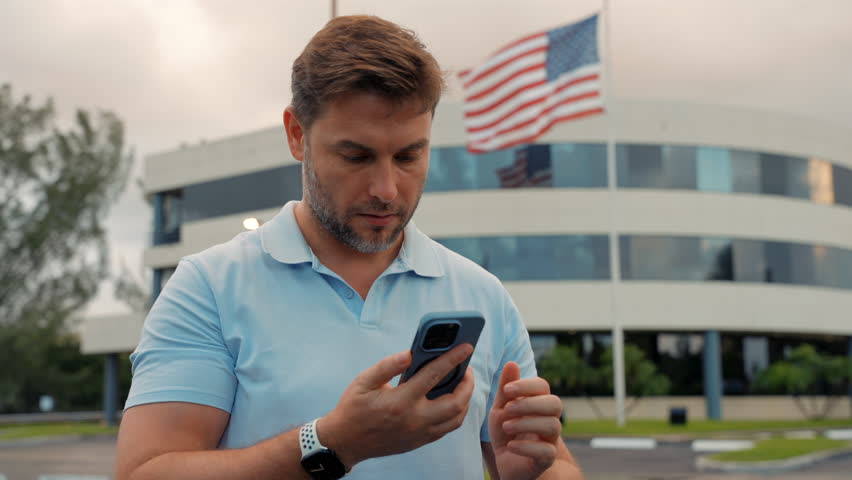 Happy middle-eastern guy talking on mobile phone. Cheerful man using mobile phone while standing outdoors. a successful businessman with a cell phone in his hands stands near the American flag