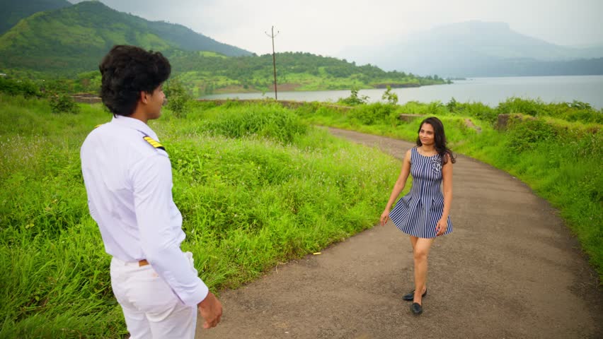 Naval Officer Approach Wife Outdoor, Pilot Walk towards Girlfriend In Scenic Outdoor Merchant Sailor walking, Toward smiling female friend, Couple hug each other, near lush meadow and hill in distant