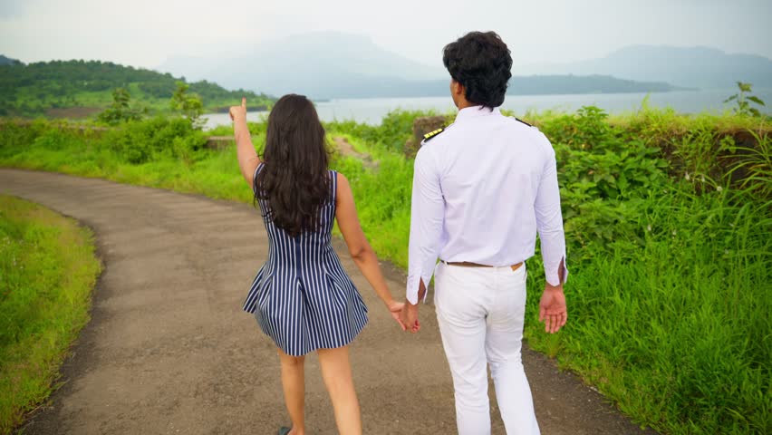 Naval Officer Walk with Wife in Nature, Pilot Holding Girlfriend and Walking At Hill Side, Merchant officer roam with spouse, On road surround by greenery, Beautiful hills, Girl point toward mountain