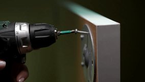 Closeup of cordless screwdriver driving screw into piece of furniture, demonstrating process of furniture assembly. Handyman assembling table, tightening screws with drill, screwing legs to table top. - Powered by Shutterstock - Get 15% off with code: PIKWIZARD15