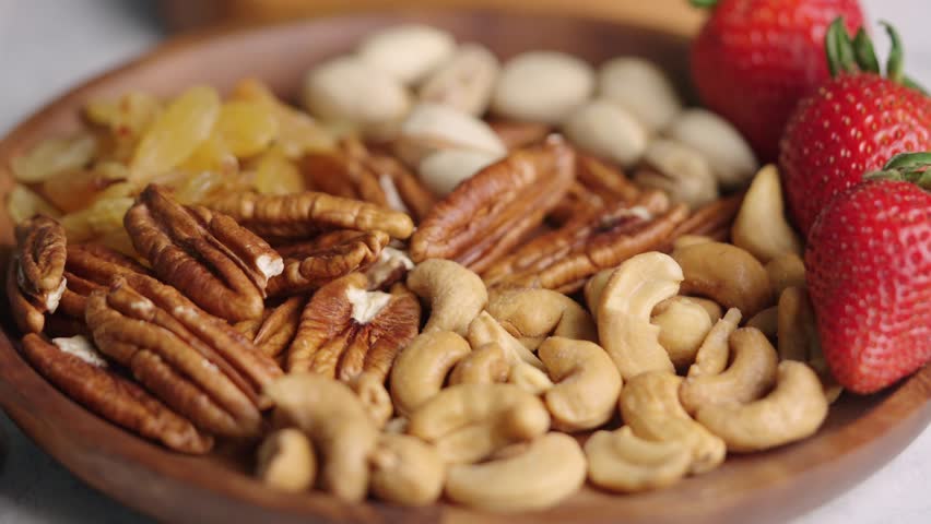 Chef arranges a colorful selection of nuts and fruits on wooden plates, showcasing a healthy and delicious snack option