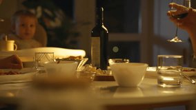 People enjoy a warm family dinner at a well-set table, featuring bowls of food and drinks. A child can be seen interacting, contributing to the lively atmosphere of the evening - Powered by Shutterstock - Get 15% off with code: PIKWIZARD15