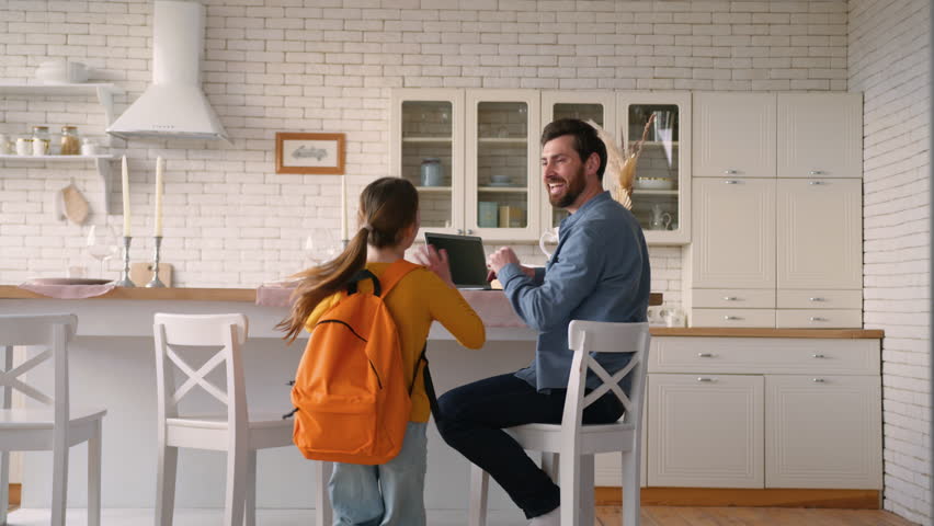 Carefree little Caucasian daughter girl kid run return home from school lessons carrying backpack education father guy man meeting child schoolgirl talk conversation male dad parent family cuddle kiss