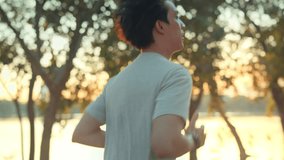 Side view - Attractive asian man jogging in the park on a background of trees with sunlight in sunset, Fitness Man Running, Training Run Workout. - Powered by Shutterstock - Get 15% off with code: PIKWIZARD15