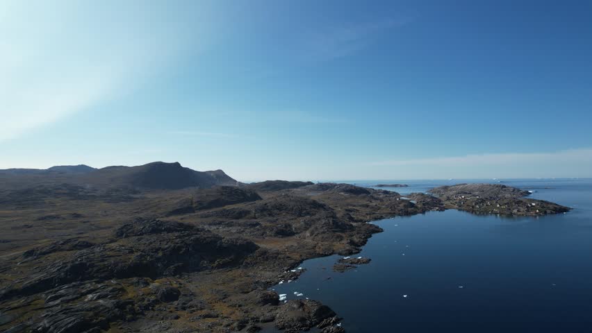 A Greenlandic landscape filmed from above, with a typical small Inuit village (settlement) in the background. Filmed in Greenland during the summer on a sunny day.