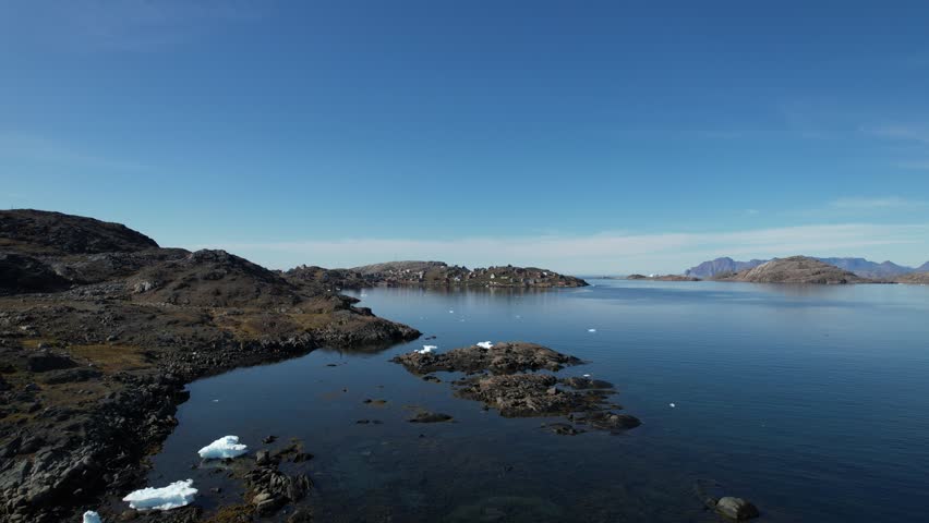 A Greenlandic landscape filmed from above, with a typical small Inuit village (settlement) in the background. Filmed in Greenland during the summer on a sunny day.