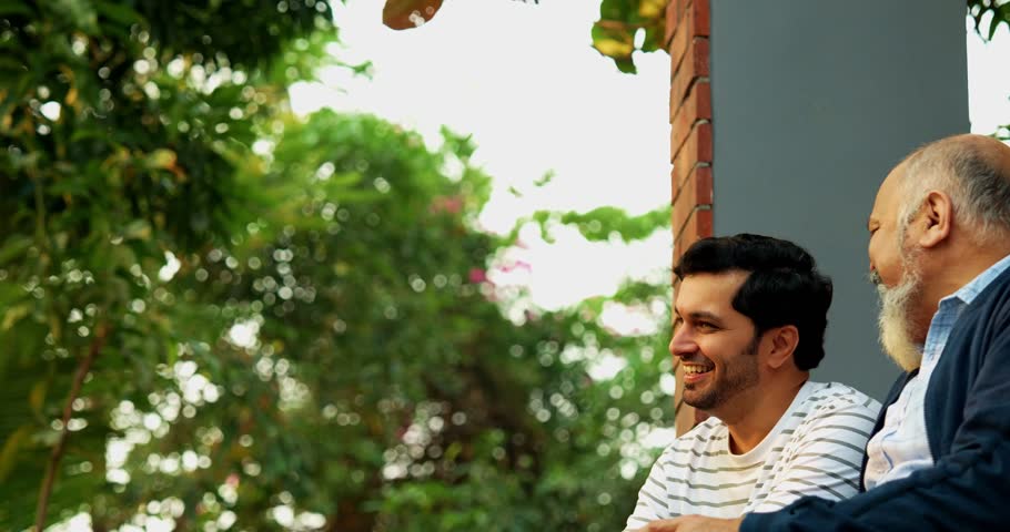 Indian Asian Happy Old Aged Father and Young Adult Son Sitting on Porch of Home Outdoors, Engaging in Heartfelt Conversation and Laughing Together, Showcasing Father-Son Bonding