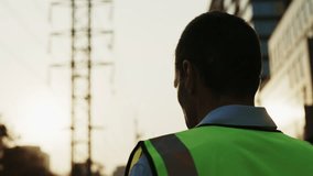 Man engineer in reflective vest puts on headwear looking away. Male worker in protective gear secures hard hat ensuring safety protocols followed in high-risk environments - Powered by Shutterstock - Get 15% off with code: PIKWIZARD15