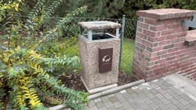Trash bin situated outdoors in close proximity to a sturdy brick wall and vibrant, lush plants at autumn. Dog waste should be disposed of in bags in European city. - Powered by Shutterstock - Get 15% off with code: PIKWIZARD15