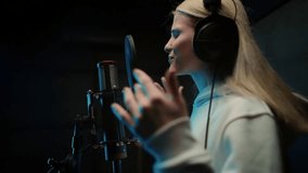 Professional singer woman performing beautiful love ballad in recording studio. Young lady recording new pop style album, star of stage, portrait of female person in room with modern sound equipment - Powered by Shutterstock - Get 15% off with code: PIKWIZARD15