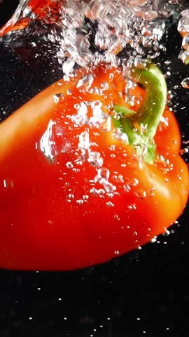 fresh red bell pepper splashing in water slow motion vertical video. fresh harvested vegetables colorful video