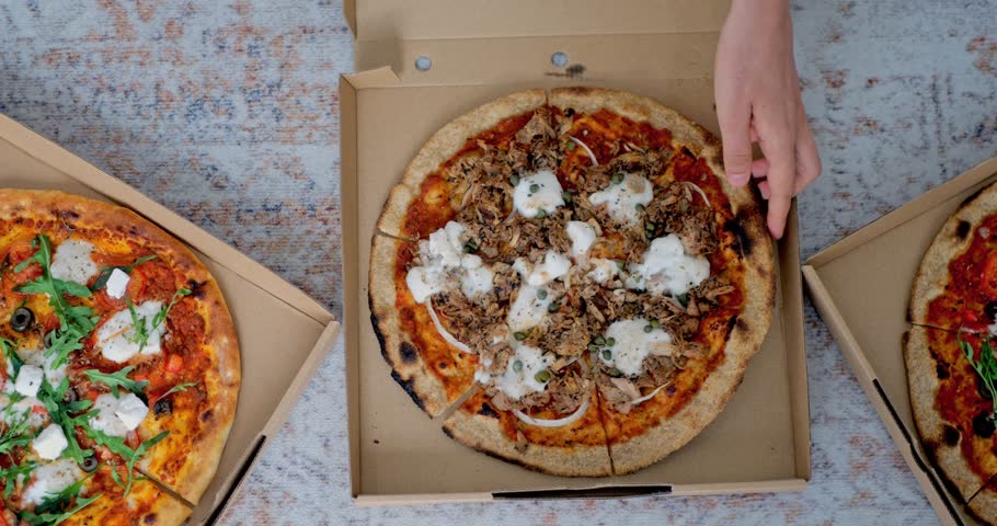 Top view of female hands taking slice of tasty vegan pizza with tomato sauce, jackfruit 