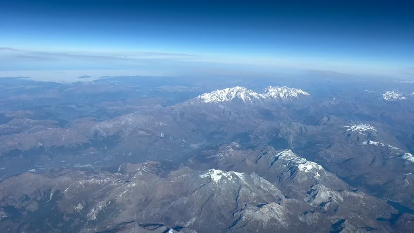 Aerial view of the Mont Blanc with little to no snow in asunny autumn morning under a blue sky seen from an airplane cockpit. Italian Alps. 4K