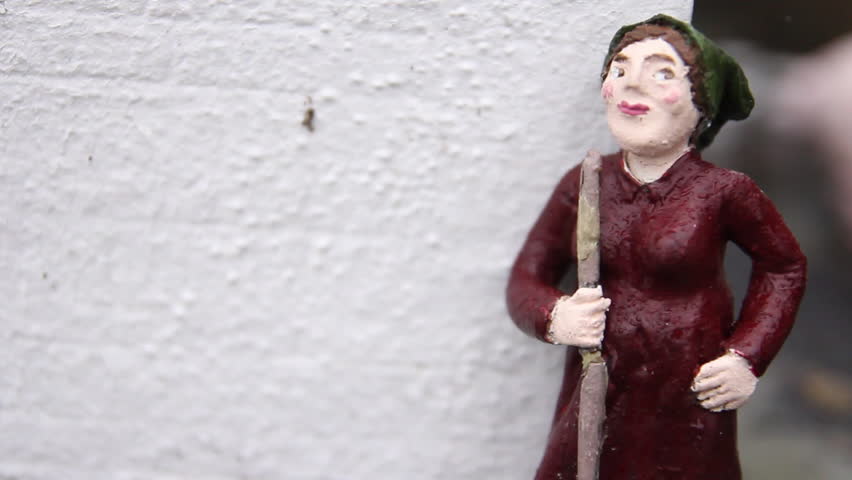A close-up of a miniature statue of a woman holding a stick, part of the Clonakilty miniature display