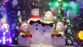 Close-up of cheerful snowmen figurines with scarves and hats inside a snow globe, surrounded by glitter and festive decorations - Powered by Shutterstock - Get 15% off with code: PIKWIZARD15