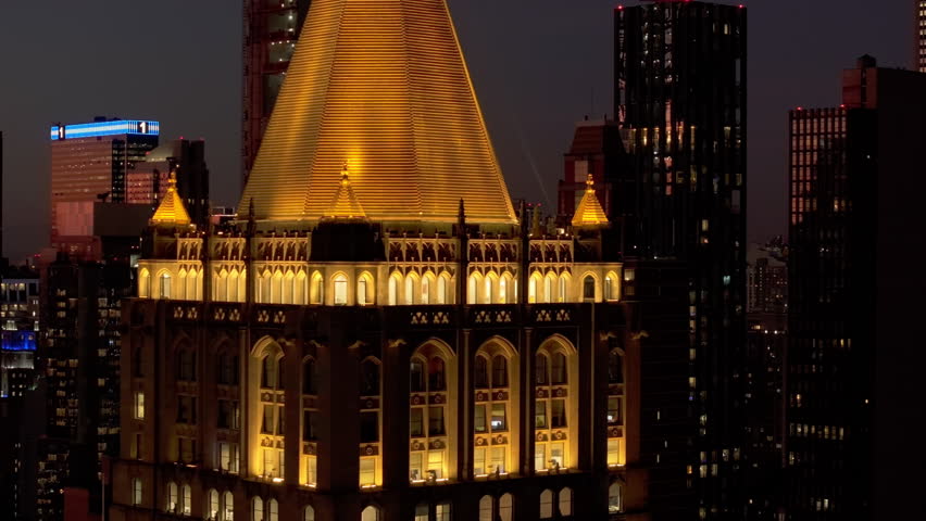 Panning around the illuminated top of New York Life Building skyscraper in Madison Avenue in Rose Hill and NoMad neighborhoods of Midtown Manhattan at night