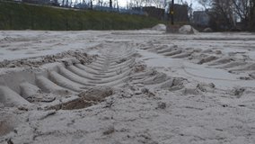 Large construction vehicle tire tracks on soft and yellow construction sand during autumn time in a cloudy day in Estonia. close up footage with a train station with trees in the background. - Powered by Shutterstock - Get 15% off with code: PIKWIZARD15