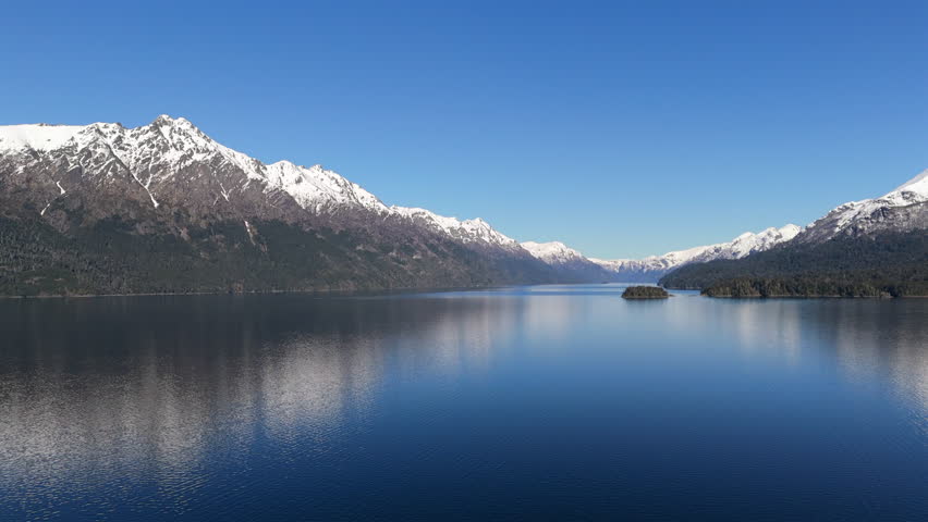 Aerial view of Nahuel Huapi Lake with a snow-capped mountain skyline.