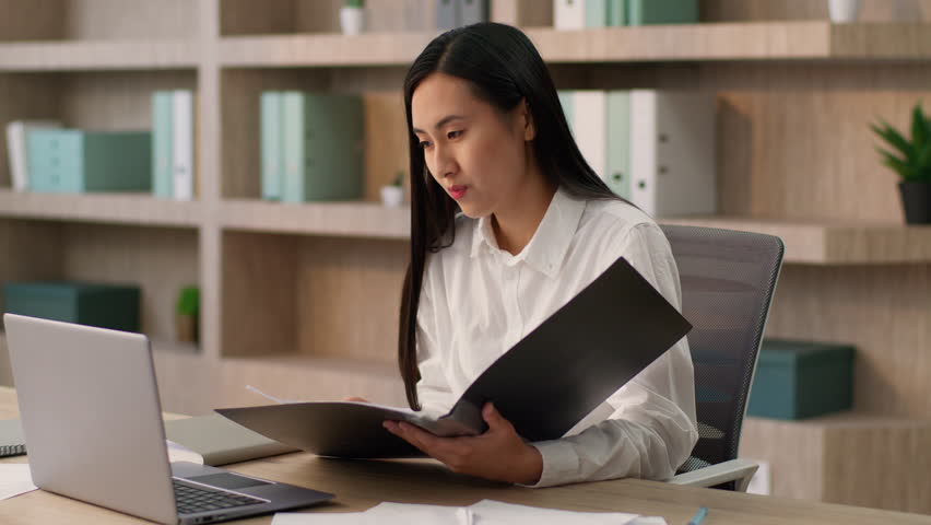 Successful Chinese businesswoman Asian girl worker Korean Japanese business woman female entrepreneur talking online laptop pc video call meeting reading contract folder documents consulting in office - Powered by Shutterstock - Get 15% off with code: PIKWIZARD15
