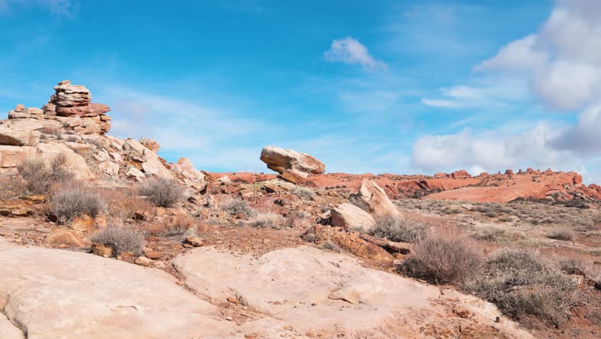 Static shot of a Large Boulder perched on the mountains of Arches National Park with a vivid blue sky in the background.