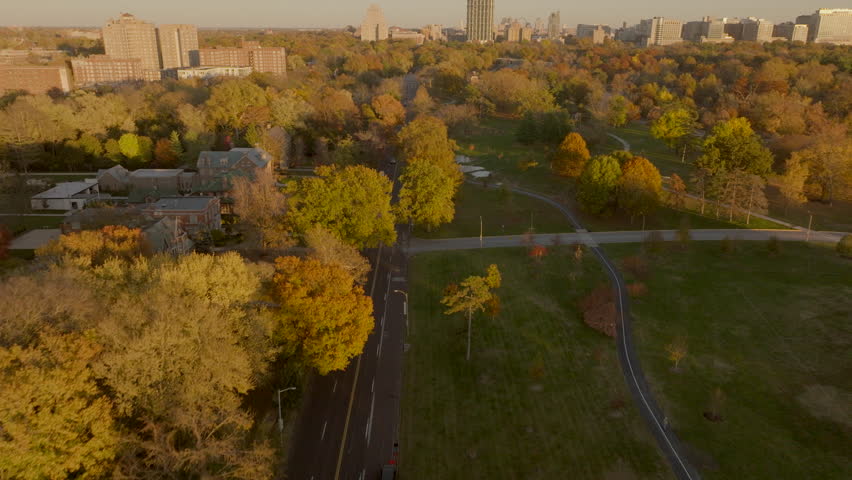 Aerial over Lindell Boulevard in St. Louis, Missouri along Forest Park and towards Central West End neighborhood on a pretty Autumn day at golden hour.