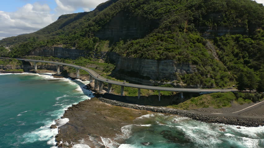 Aerial pan of famous Sea Cliff Bridge by hilly coast of southeast Australia