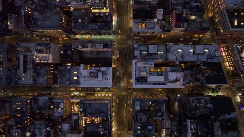 Bird's eye view of Manhattan streets in New York illuminated at night, showcasing vibrant city life and architecture from above with glowing lights and bustling activity