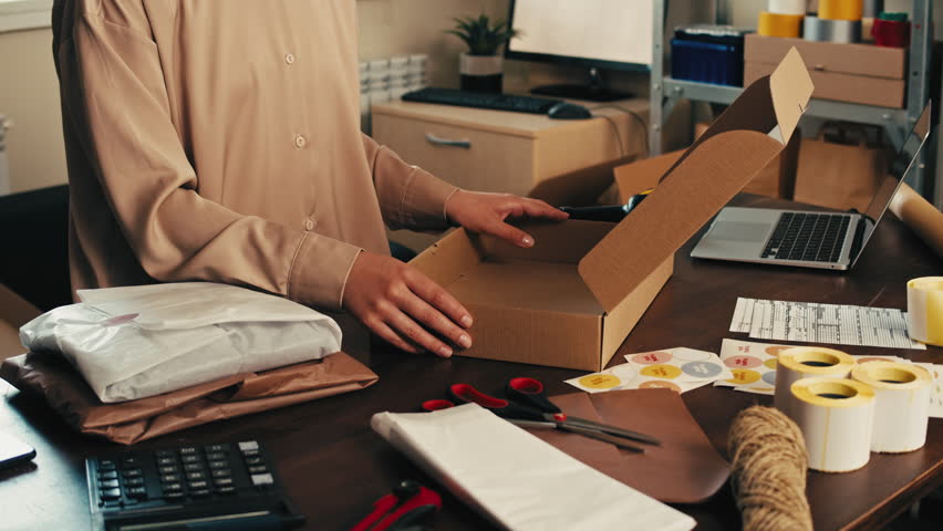 E-commerce storage shop, woman packing goods and clothes for second hand delivery market, dedicated Packaging and Shipping Workspace with Supplies and Technology for efficiency, online sales.